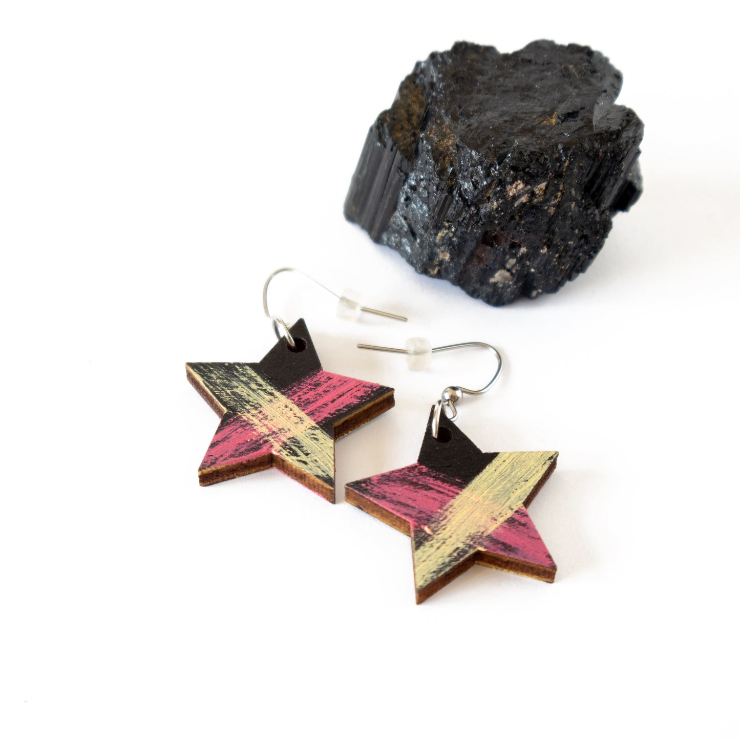 Black unique wooden earrings in the shape of a star with pink and yellow details